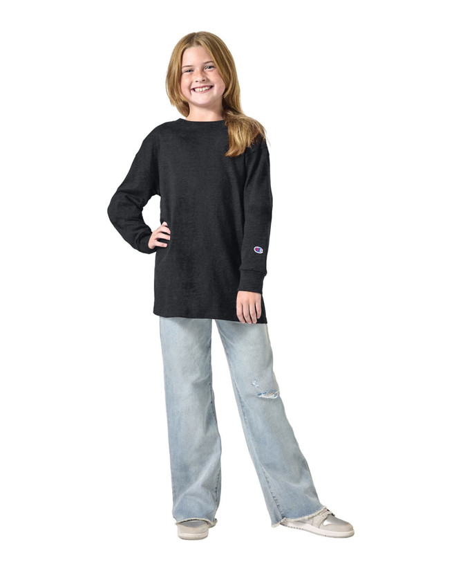 A youth long sleeve t-shirt in black, worn with light blue ripped jeans, featuring a logo on the sleeve.
