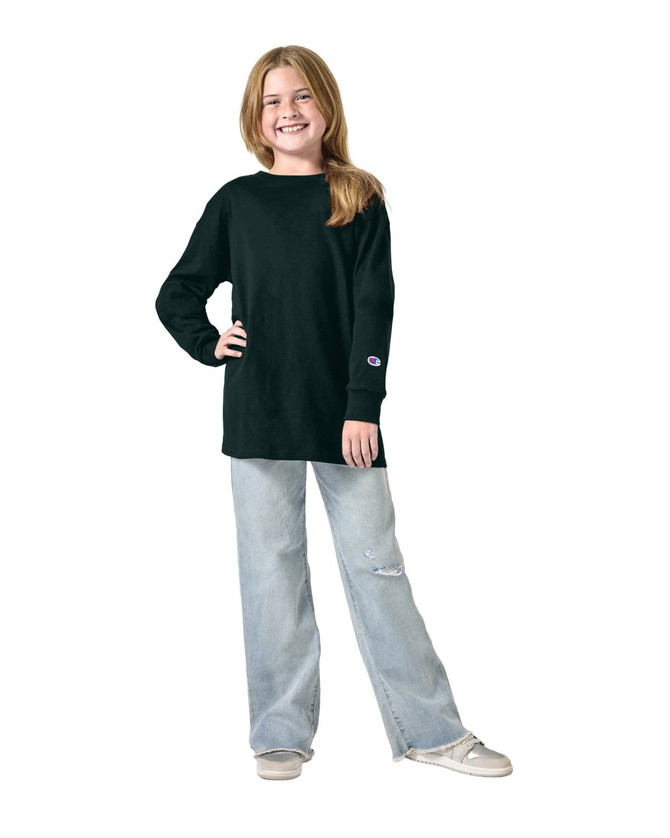 A youth long sleeve t-shirt in black, worn by a child paired with light wash jeans. Features a logo on the sleeve.