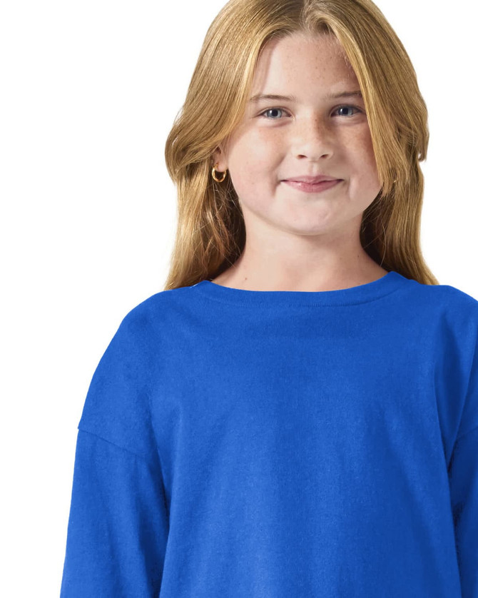 A blue long sleeve youth t-shirt displayed on a smiling child, featuring a simple crew neck design and one logo.