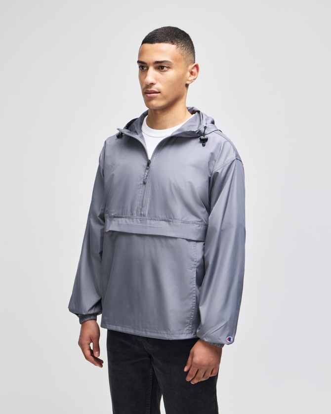 A grey packable anorak jacket features a hood, half-zip front, and a logo on the chest. Suitable for rain protection.