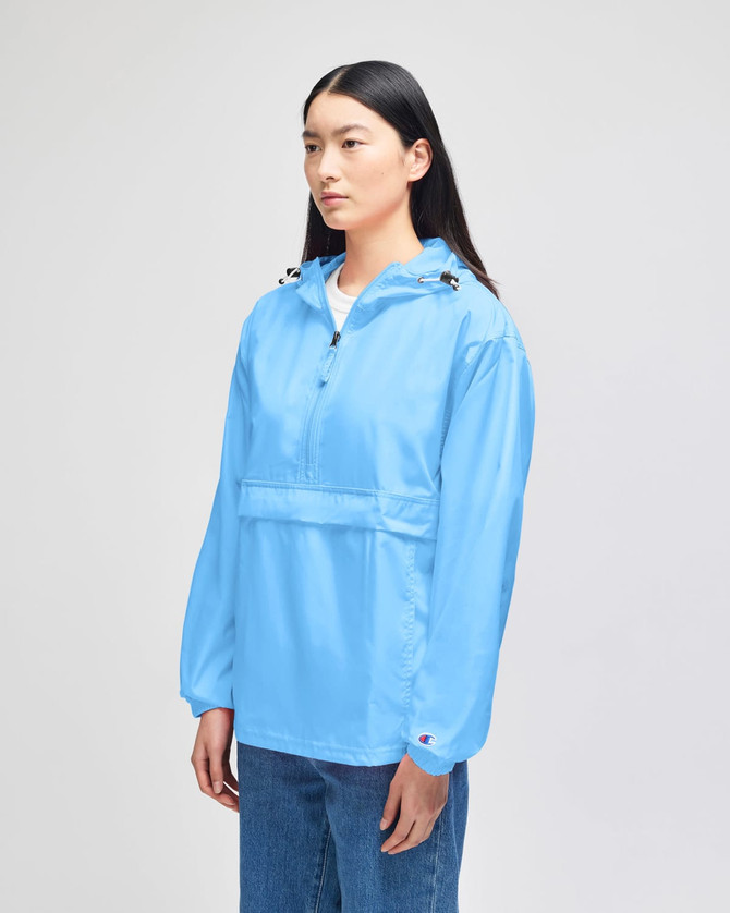 A blue packable anorak jacket with a half-zip and hood, featuring a logo on the sleeve.