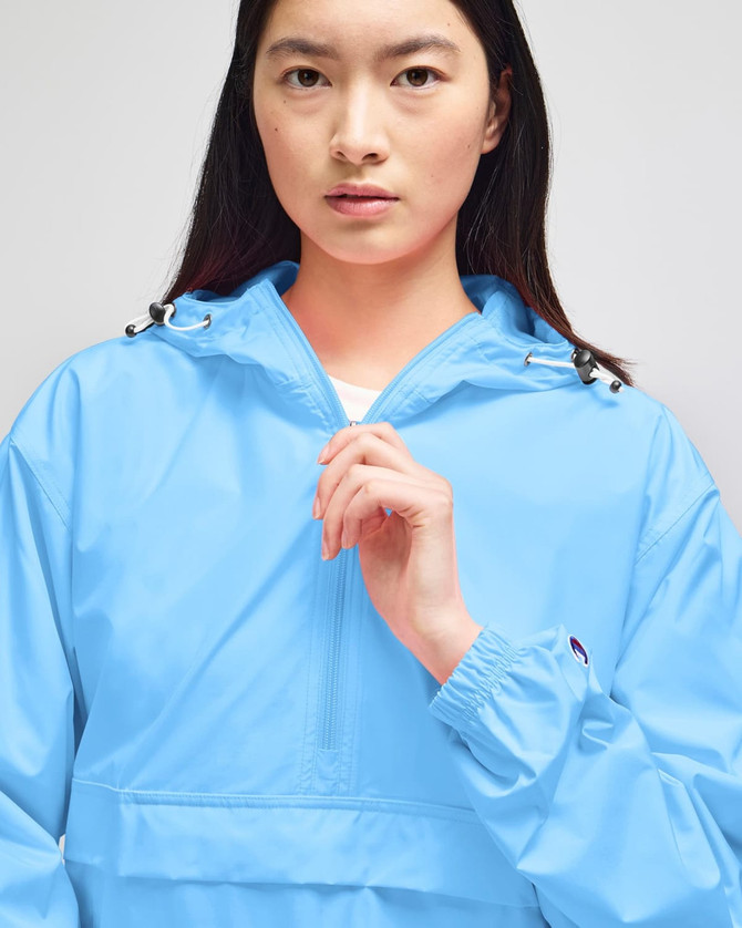 A light blue packable anorak jacket with a hood, featuring an adjustable neckline and cuff details.