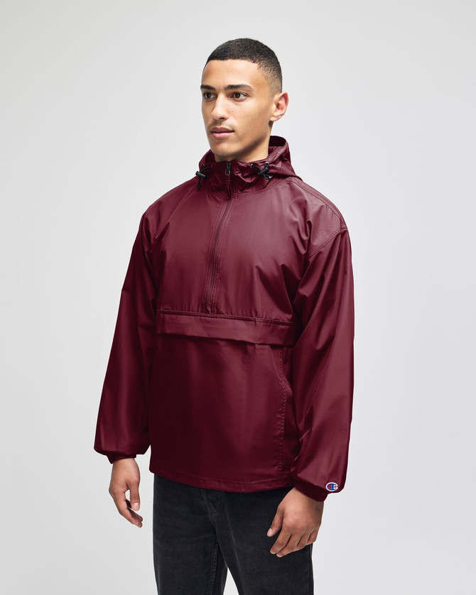A maroon packable anorak jacket with a hood and a logo, worn by a model standing against a neutral background.