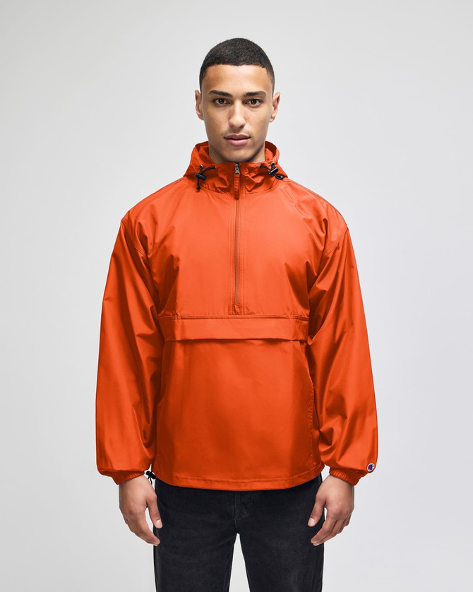 An orange packable anorak jacket with a hood and a front pocket, featuring a logo on the chest.