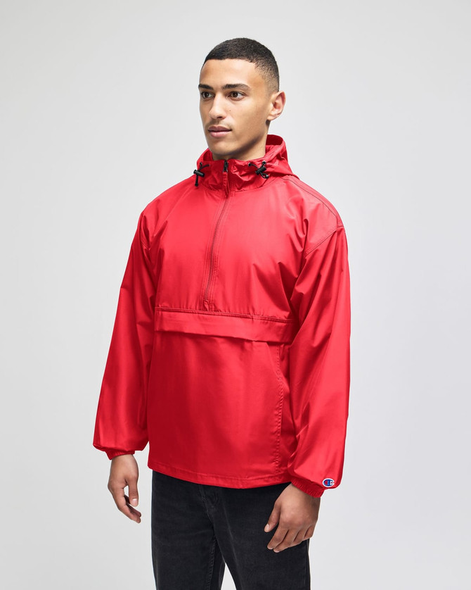 A red packable anorak jacket with a half-zip and hooded design, featuring a logo. Model wearing black pants.