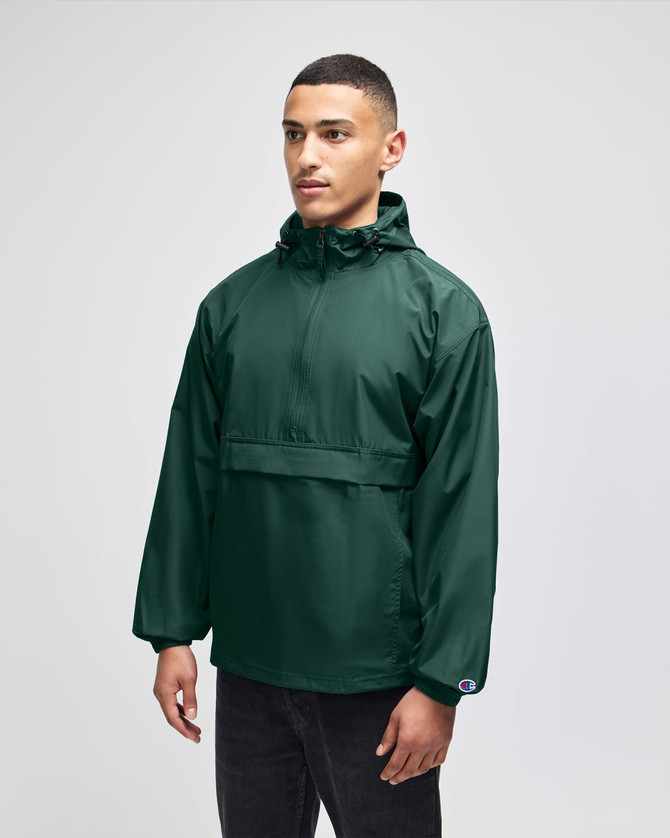 A model wearing a green packable anorak jacket with a hood, featuring a front pocket and a logo.