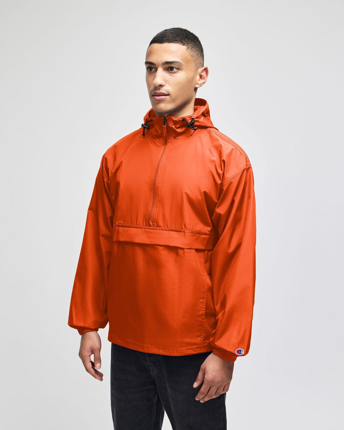 An orange packable anorak jacket with a hood and front pocket, featuring a logo on the sleeve.