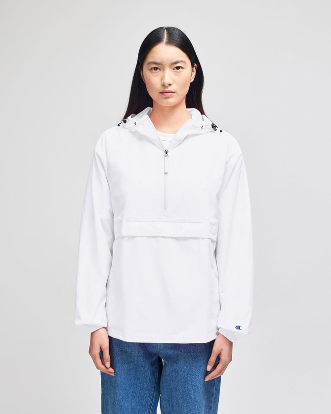 A white packable anorak jacket with a hood and a front pocket, featuring a logo. Model is wearing blue jeans.