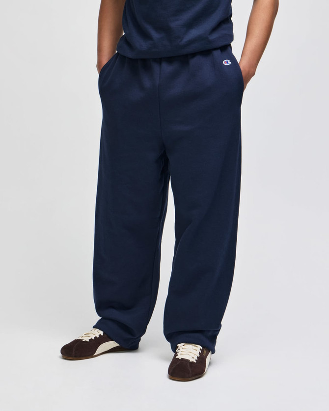 Navy fleece track pants with an open bottom and pockets, featuring a branding logo on the waistband.
