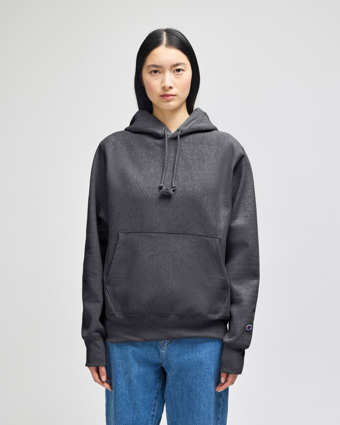 A women's cropped hoodie in dark grey with a front pocket and a logo on the sleeve.