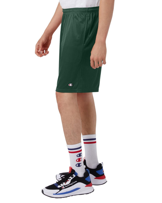 Green sports shorts with pockets, featuring a logo, displayed on a model alongside sneakers and socks.