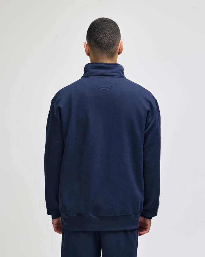 A navy quarter-zip pullover jacket viewed from the back, featuring a high collar and a simple design.