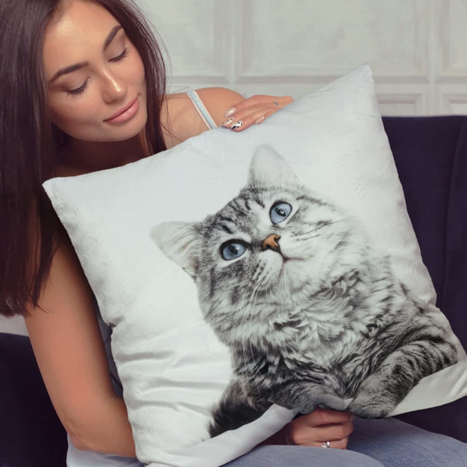 A plush cushion featuring a detailed cat image, with a woman holding it against a soft backdrop.