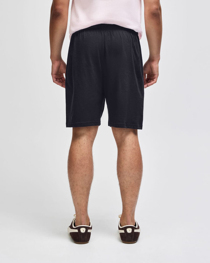 Black gym shorts with an elastic waistband, viewed from the back, featuring a simple design and branding.
