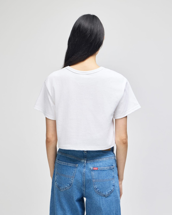A white cropped short sleeve t-shirt displayed from the back, paired with blue jeans. The shirt features a logo.