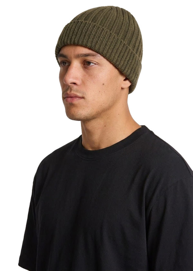 A beanie in olive green displayed on a model wearing a black t-shirt, featuring ribbed texture.
