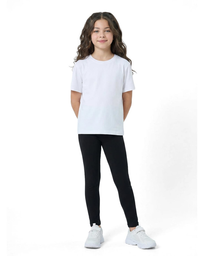 A child wearing black leggings paired with a plain white T-shirt and white sneakers, smiling confidently.