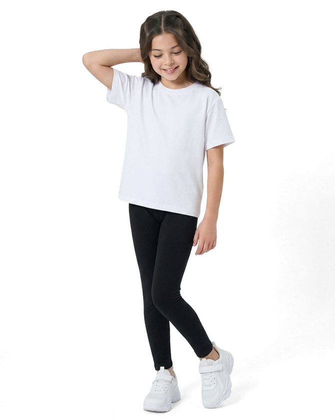 A girl in a white t-shirt and black leggings poses in white sneakers, showcasing the kids' legging design.