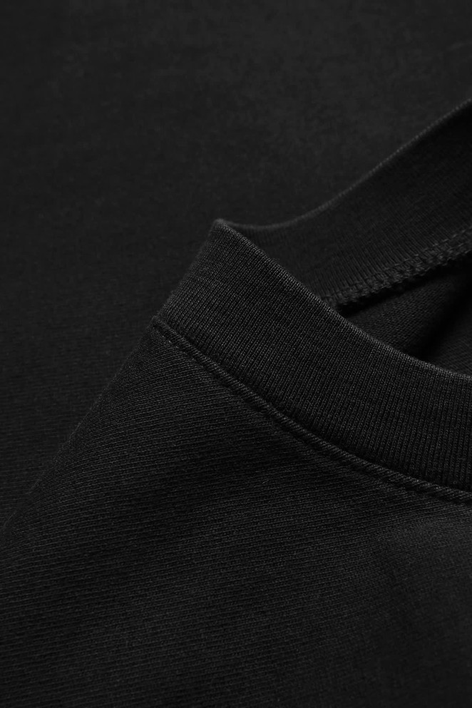 A close-up of a black oversized T-shirt featuring a round neckline and soft fabric texture.