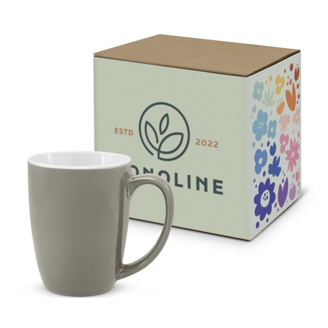 A green coffee mug beside its decorative box, featuring a floral design and branding.