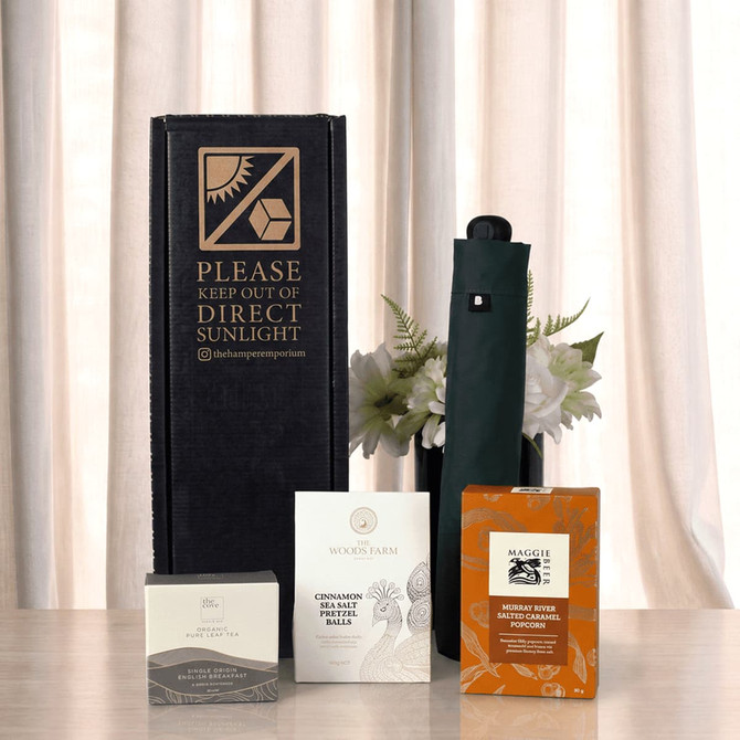 A set featuring a dark green umbrella, a drink bottle, and various packaged items on a neutral backdrop.