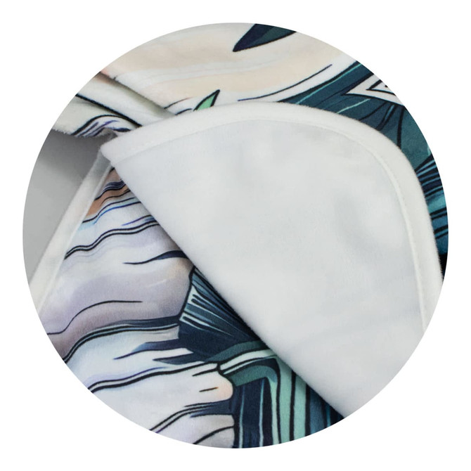 A blanket featuring vibrant colours and intricate patterns, with a soft white underside. It has branding visible.