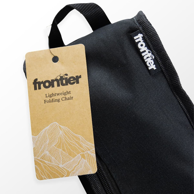 A black carrying bag for a lightweight folding chair, featuring a tag with a mountain design and branding.