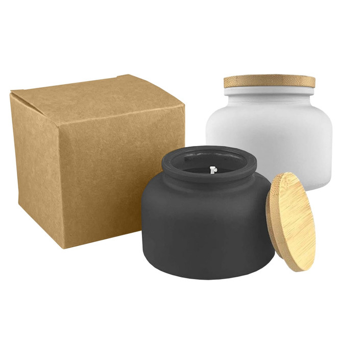 A black candle jar with a wooden lid next to a white candle jar, both with a brown box.