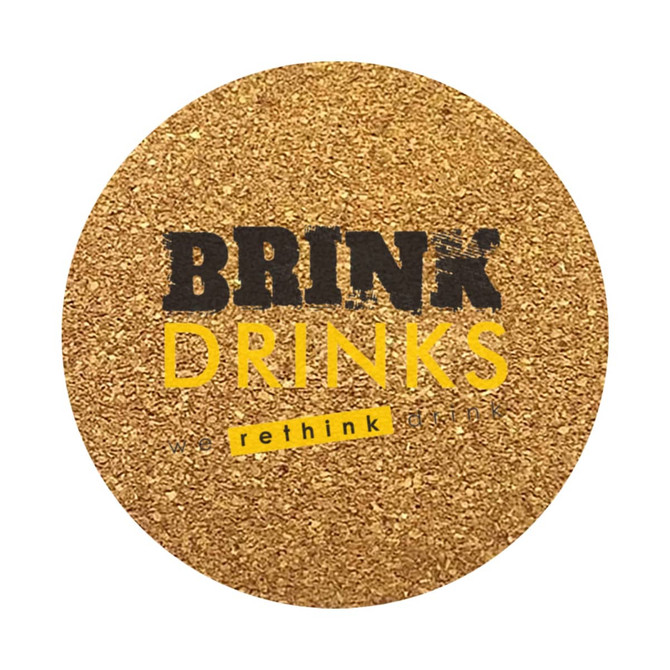 A round cork coaster with a textured golden surface and a logo in black and yellow.