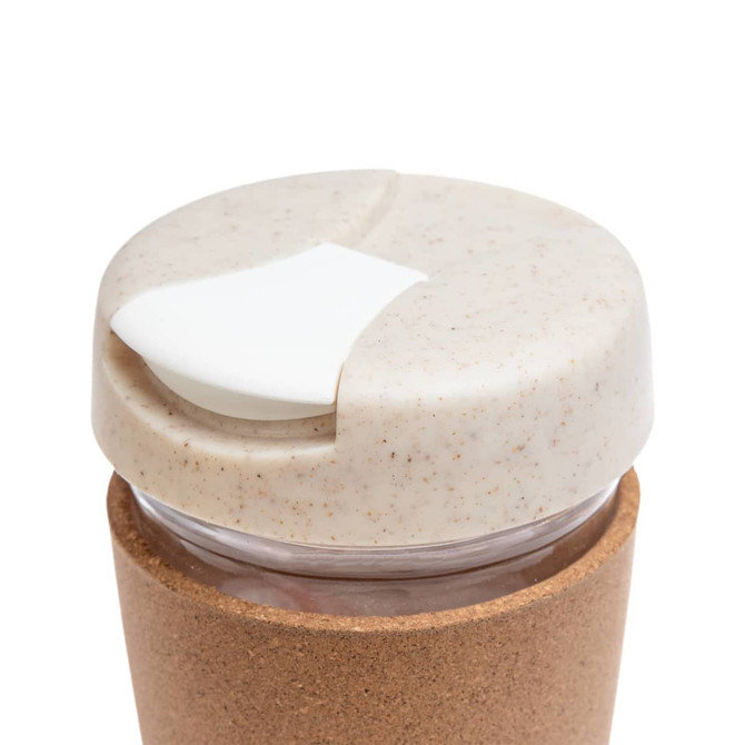 A reusable coffee cup with a cork band and a light-colored lid featuring a sliding opening.