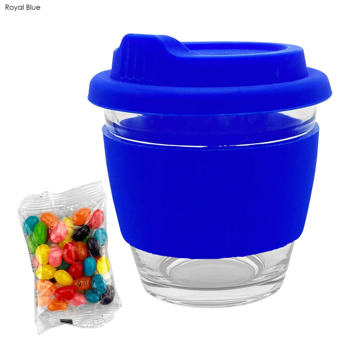 A reusable glass coffee cup in royal blue featuring a silicone sleeve, accompanied by a pack of colourful jelly beans.