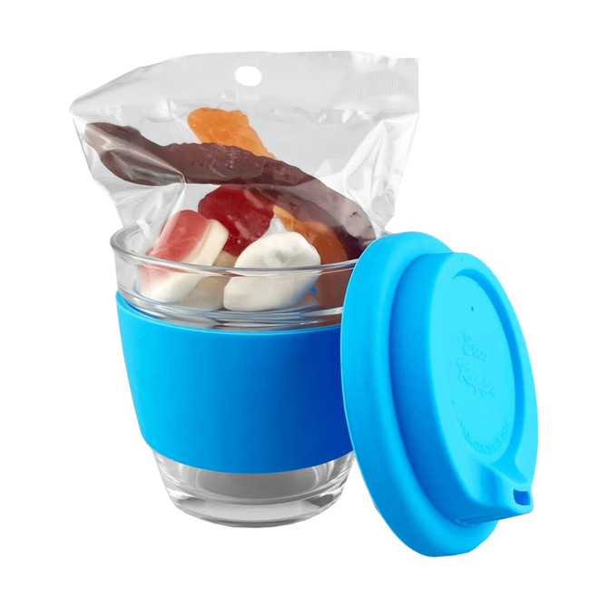A glass coffee cup with a blue silicone sleeve, filled with assorted jelly lollies inside a sealed bag.