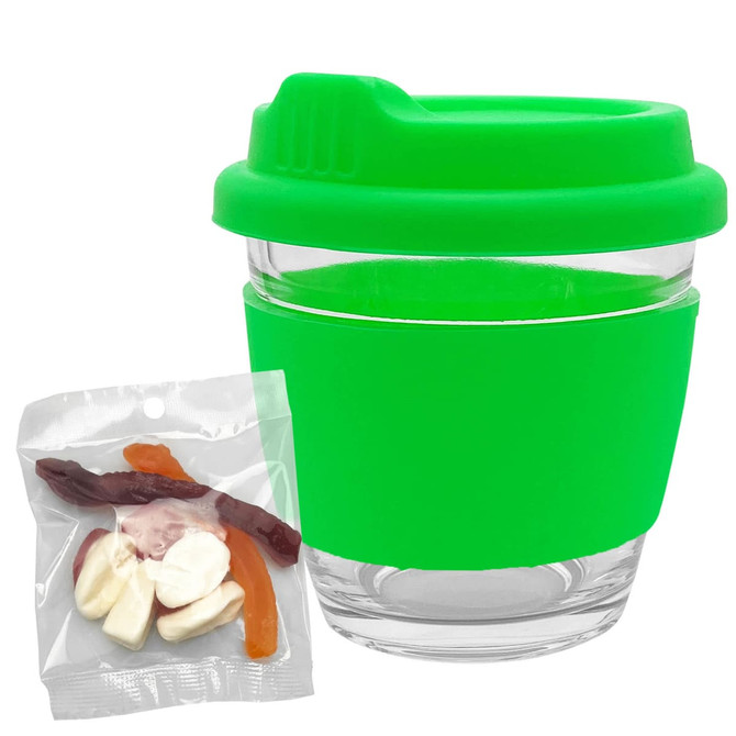 A green Venice glass coffee cup with a matching lid, accompanied by a pack of mixed lollies in various colours.