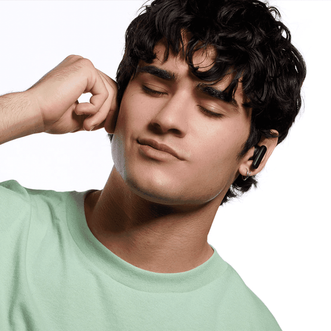 A young man wearing black earbuds, enjoying music, with tousled dark hair and a mint green t-shirt.