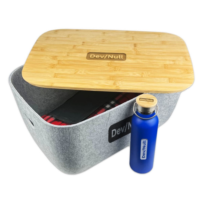 A grey storage tub with a bamboo lid and a blue drink bottle. The tub contains a patterned blanket.