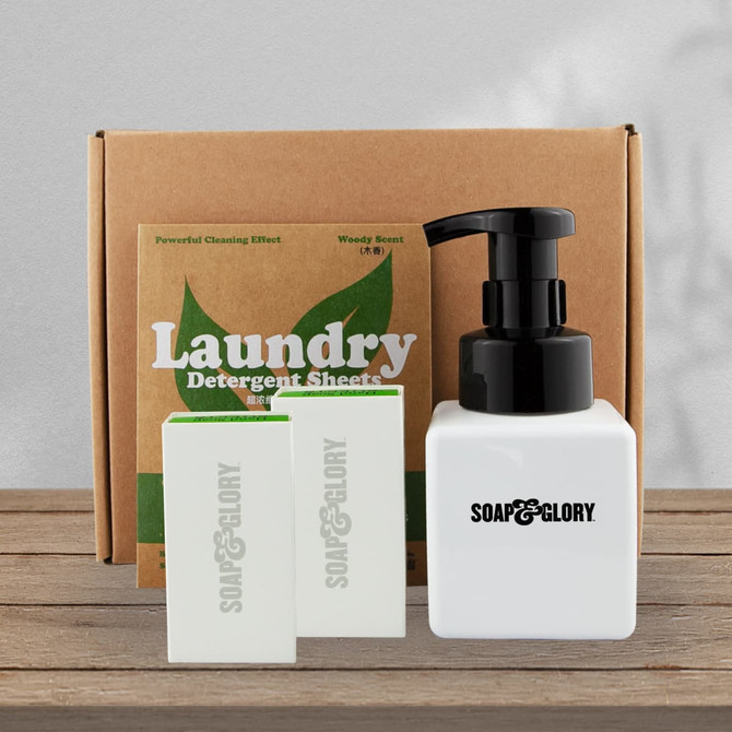 A white pump bottle with black lid beside three soap bars, placed in a brown box labelled "Laundry."