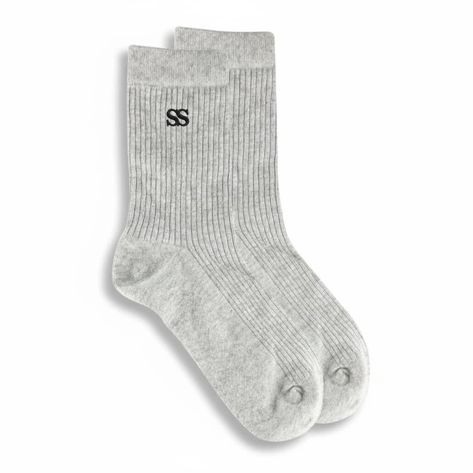 A pair of grey lounge socks featuring a ribbed texture and a logo on one side.