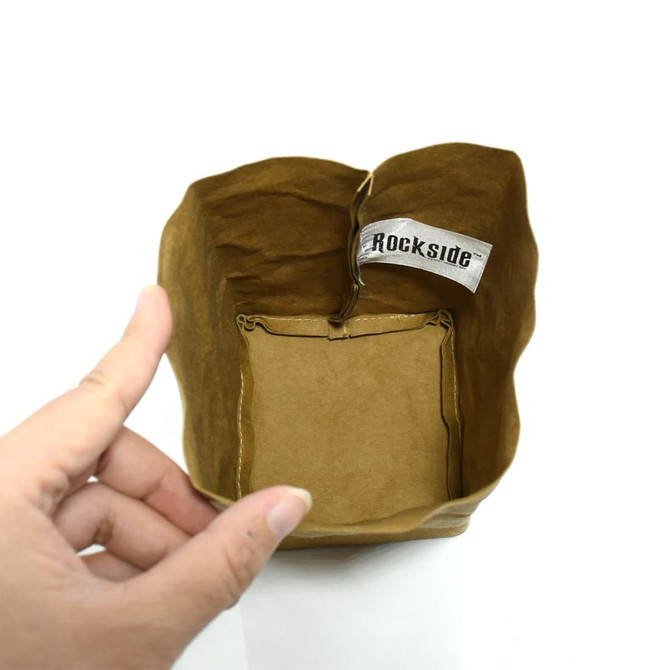 A small brown kraft paper storage bag with a decorative tag inside, being held by a hand.