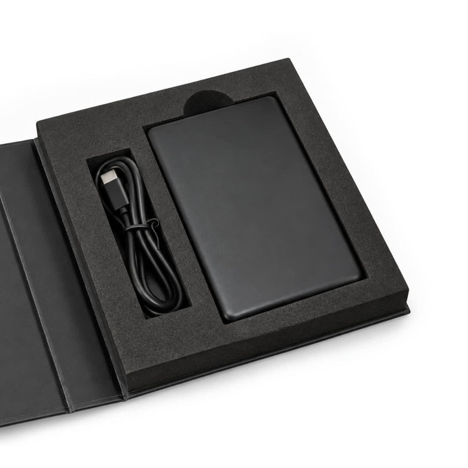 A black solid-state power bank with a USB cable, displayed in a black presentation box.