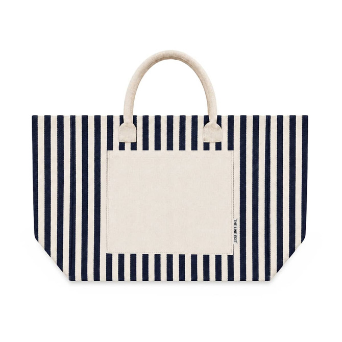 A striped tote bag featuring navy blue and cream colours with two handles and a front pocket. It has a logo.