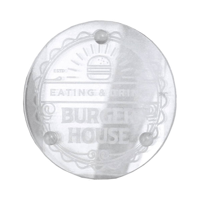 A clear round glass coaster with a logo design and four small feet for stability.
