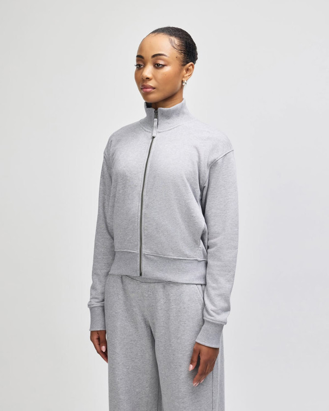 A grey women's full-zip jacket in French terry fabric, featuring a high collar and relaxed fit.