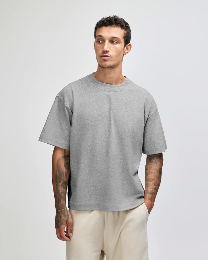 A grey heavyweight cotton unisex boxy t-shirt displayed on a model, featuring a relaxed fit and short sleeves.