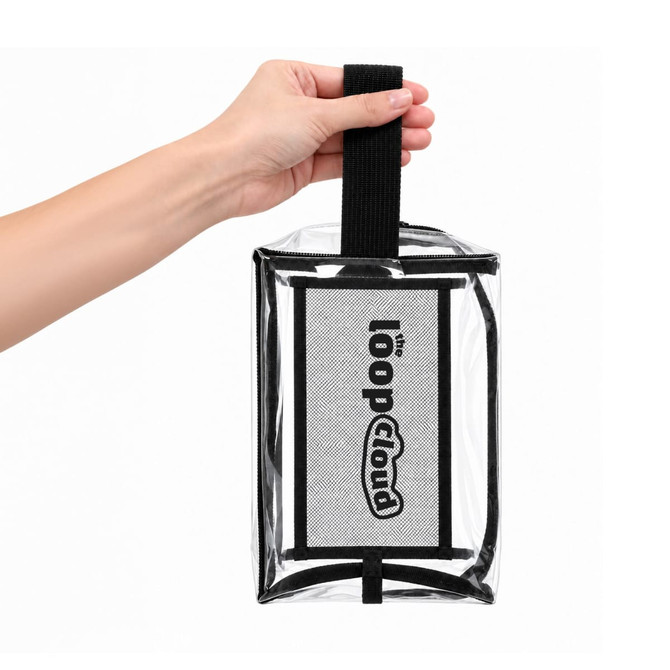 A clear cosmetic bag with a black handle and a branded logo, held by a hand.