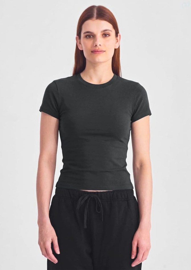 A women's baby tee in dark green, featuring a fitted design and short sleeves, with a model standing against a neutral background.