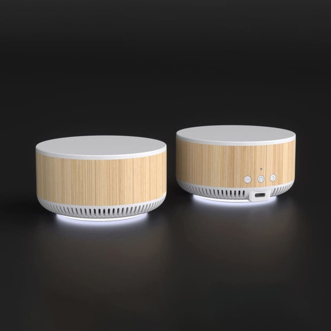A wireless charging speaker with a bamboo finish and white accents, featuring buttons and a charging port on the side.