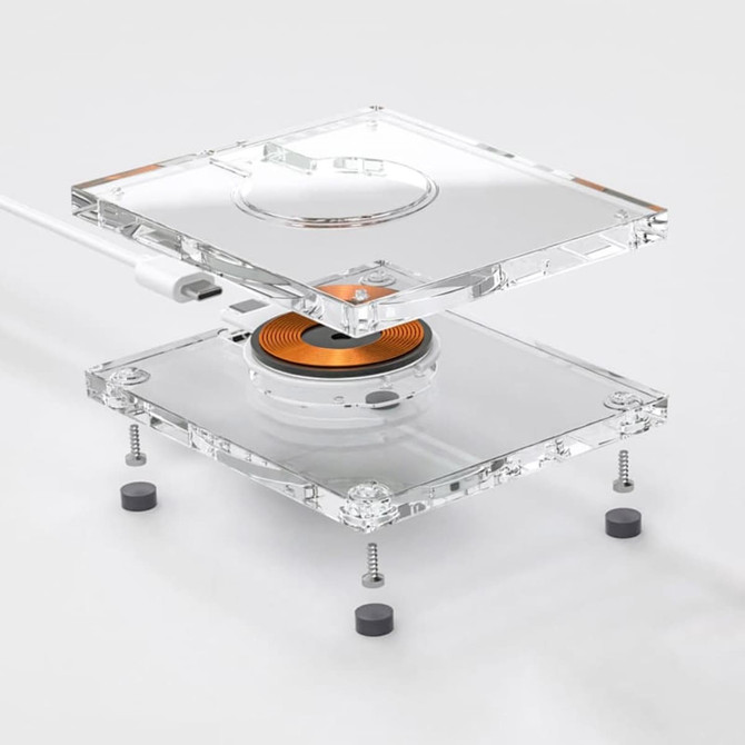A transparent acrylic wireless charger with a circular charging pad and visible internal components.