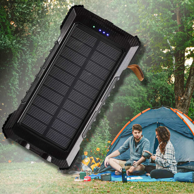 A black solar power bank with multiple charging ports, set against a camping scene with a tent and two people.