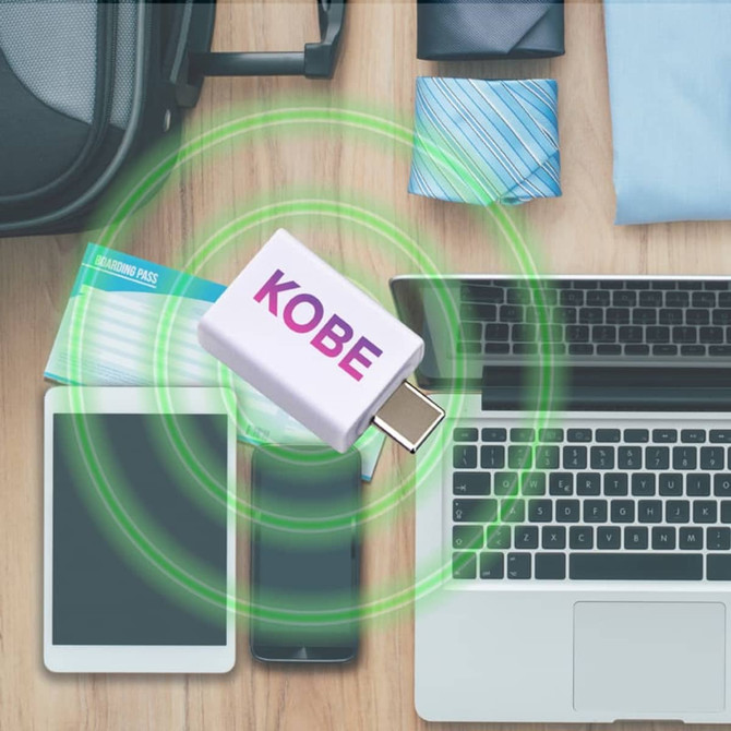 A white Type-C to Type-A data blocker is centred among a laptop, tablet, and smartphone on a wooden surface.