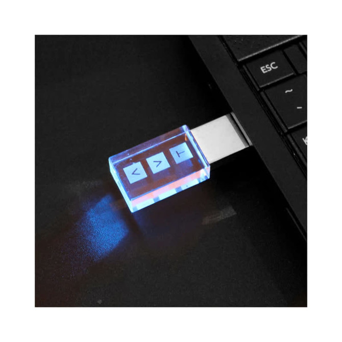 A 3D crystal flash drive with a transparent blue casing, plugged into a laptop's USB port, emitting a soft glow.